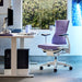 A Herman Miller X Logitech Embody Gaming Chair in purple Amethyst as part of a gaming setup.